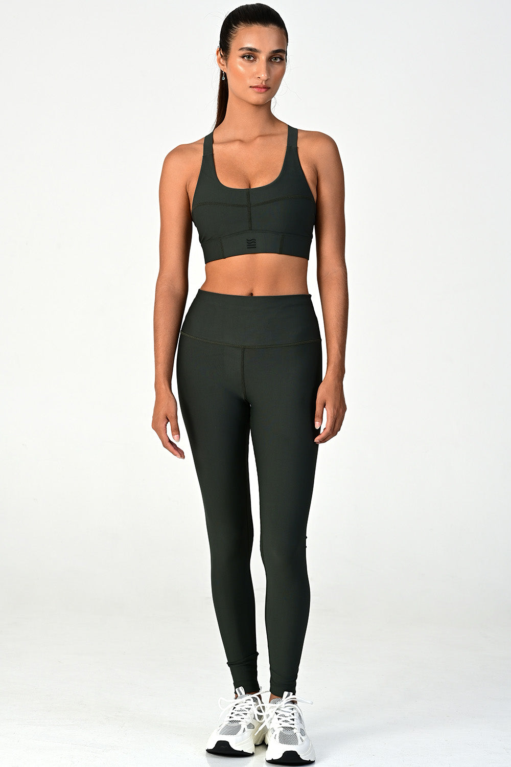 Front view of a woman wearing the Soho dark olive active legging on a white background
