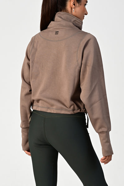 Back view of a woman wearing the Rodeo khaki oversized half zip on a white background
