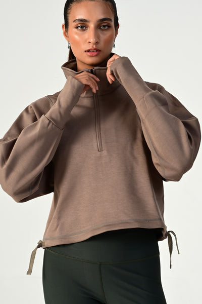 Zoomed front view of a women wearing the Rodeo khaki oversized half zip on a white background