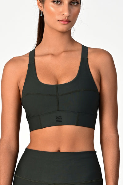 Front view of a woman wearing the Soho dark olive active bra on a white background