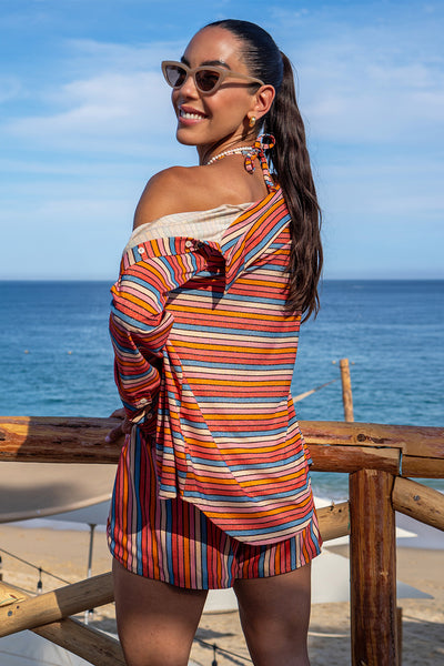 Back view of a woman wearing the Raya Stripes Short & Shirt Set on a beach background. 