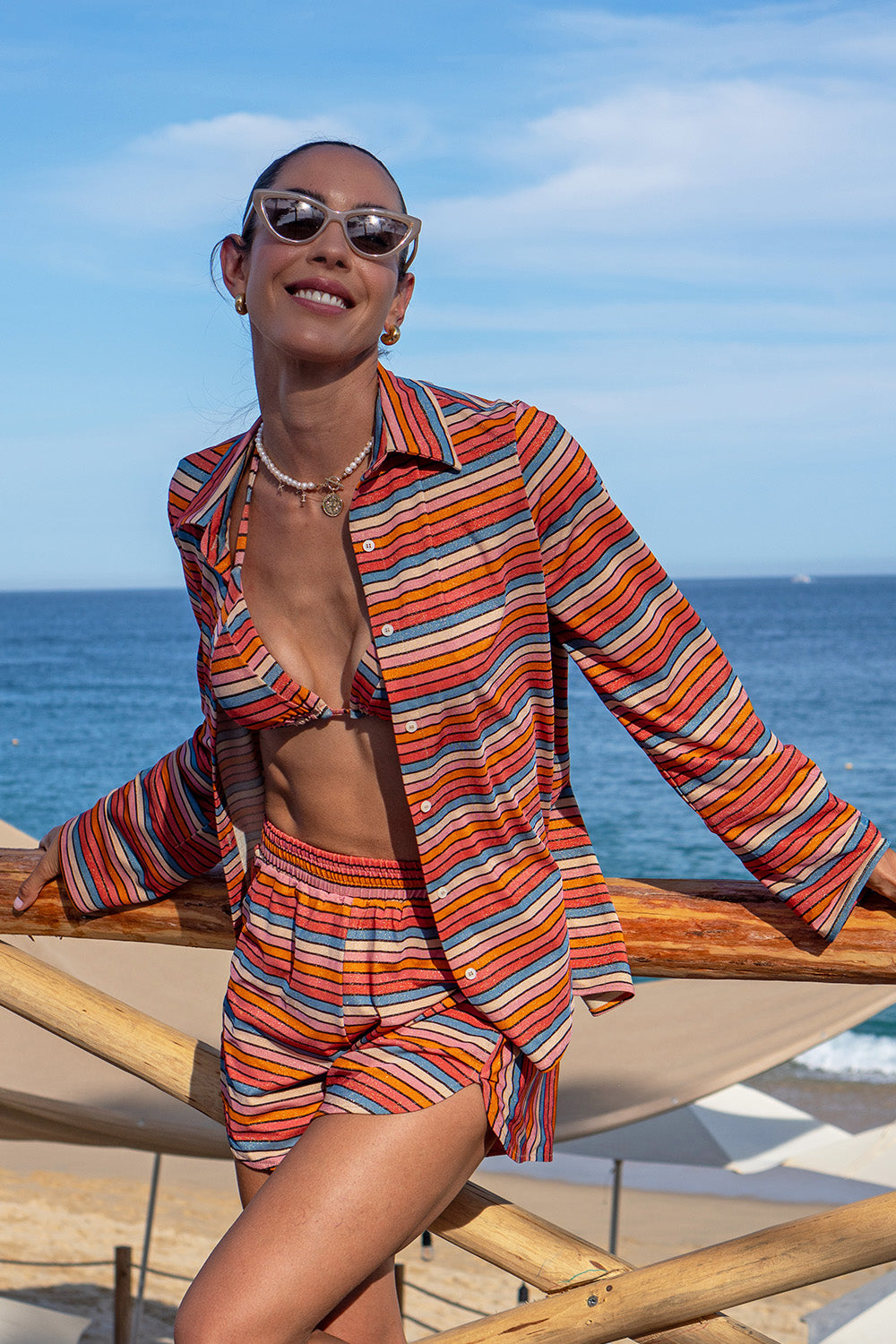 Front view of a woman wearing the Raya Stripes Short & Shirt Set on a beach background. 