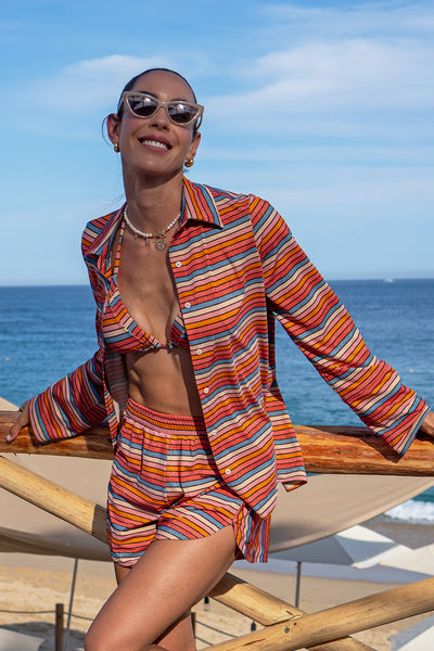 Front view of a woman wearing the Raya Stripes Short & Shirt Set on a beach background. 