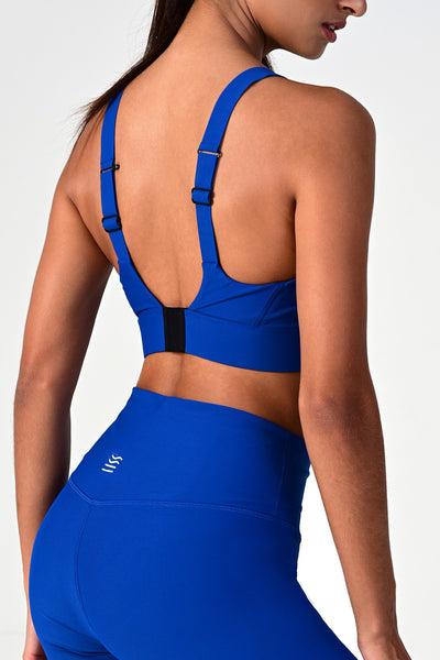 Back side view of a woman posing wearing the Soho cobalt active bra top.