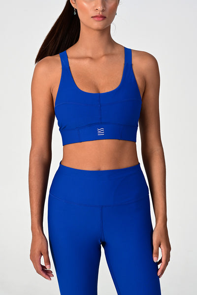 Front view of a woman posing wearing the Soho cobalt active bra top.