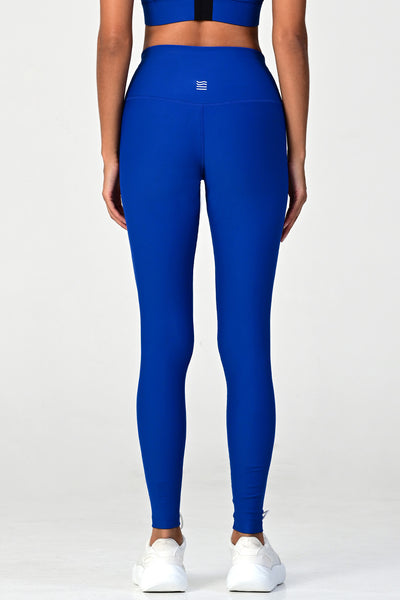 Back view of a woman posing wearing the soho cobalt active legging.