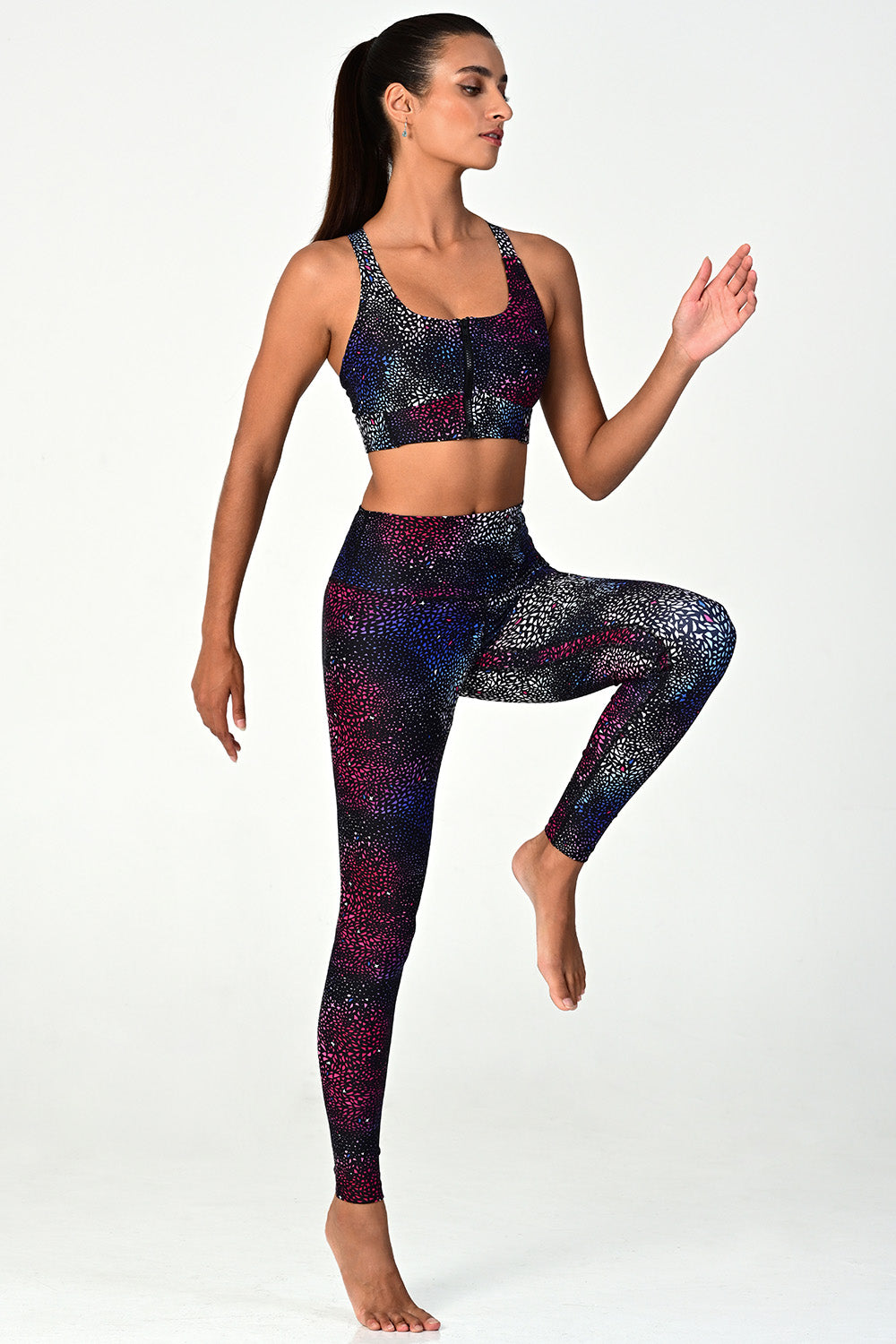 Woman wearing the Soho Galaxy active legging jumping on white background side view. 