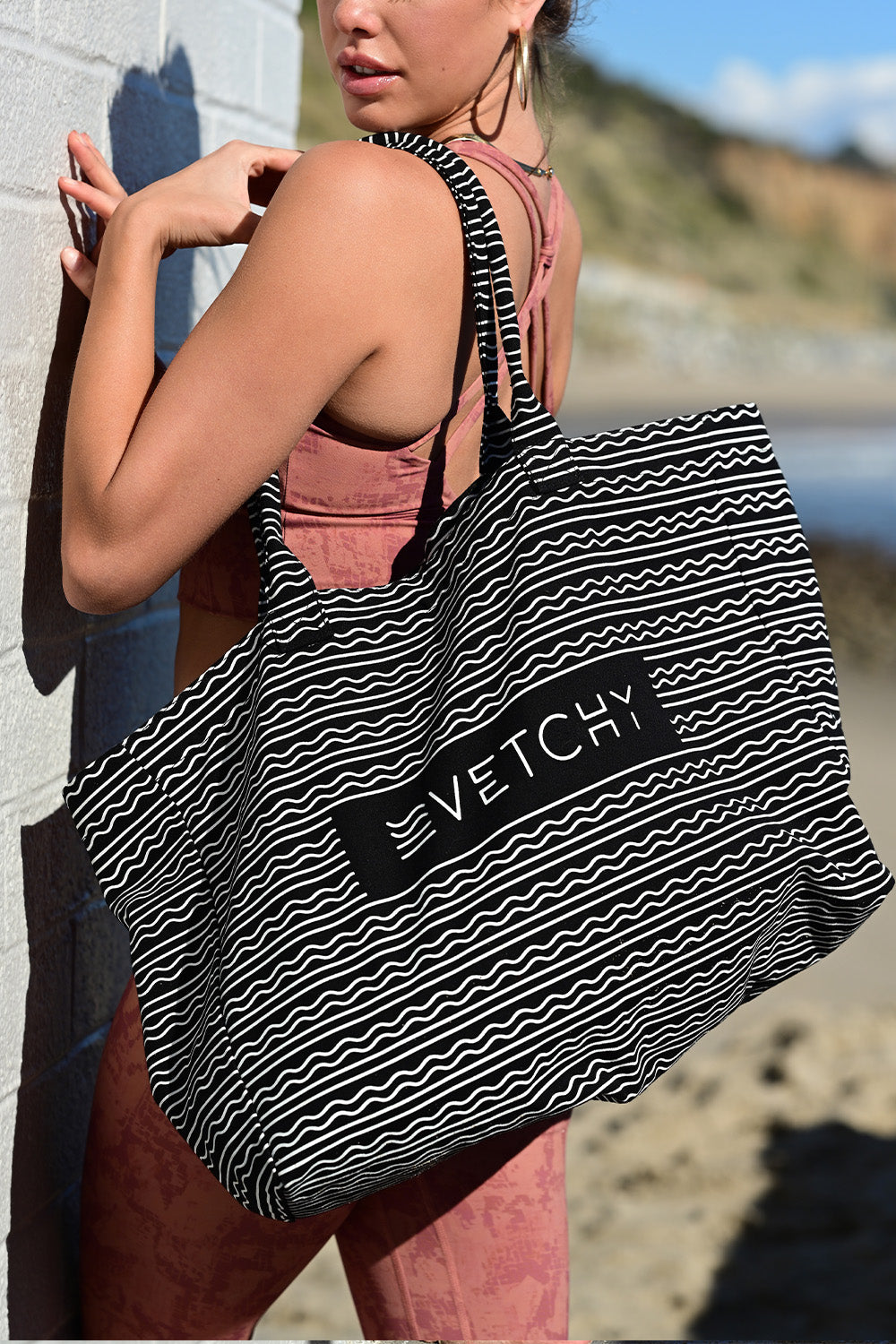 Zoomed side view of a women carrying the Vetchy tote bag on the beach background 