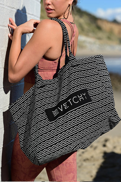 Zoomed side view of a women carrying the Vetchy tote bag on the beach background 
